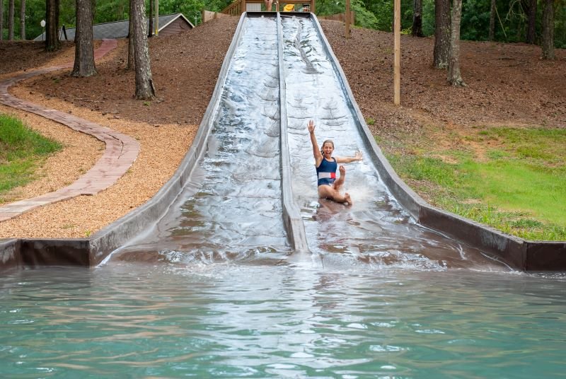 ids enjoying a waterslide into the lake at Kick Back Ranch, a family-friendly campground near Montgomery, AL