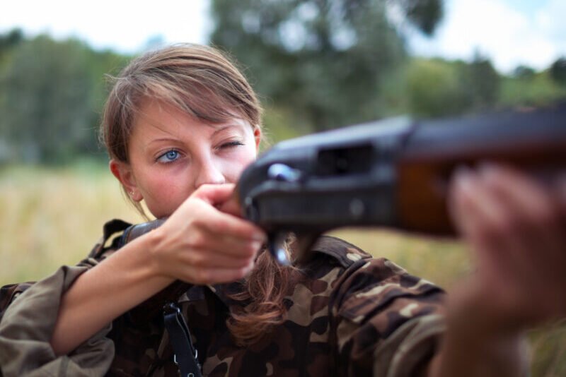 A young girl with a gun aiming at a target