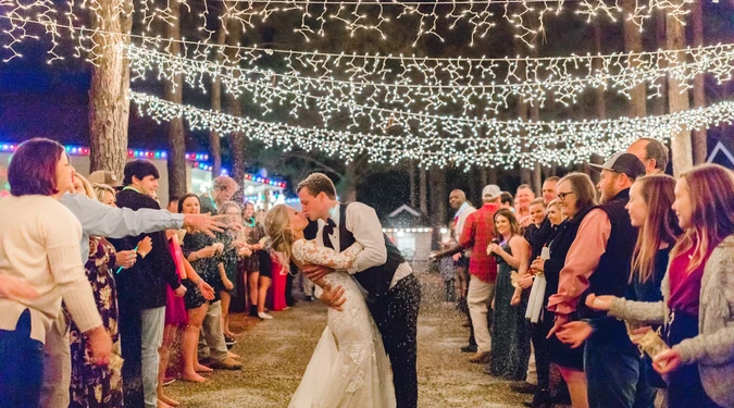 Bride and groom make their grand exit through Cowboy Town at Kick Back Ranch during a rustic wedding celebration.